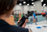 A woman is holding a Two-Way Radios at a trade show.